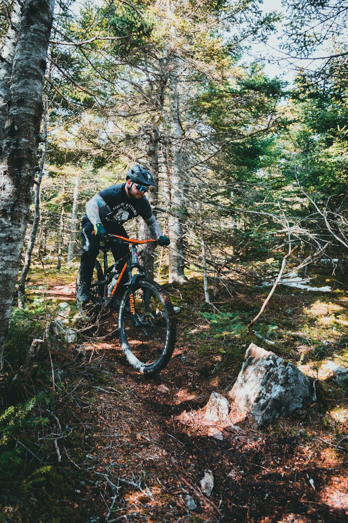 Man rides a mountain bike through a dense forest trail, showcasing adventure and outdoor activity.
